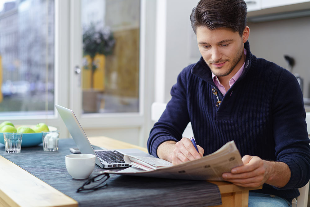 man reading the newspaper in his kitchen