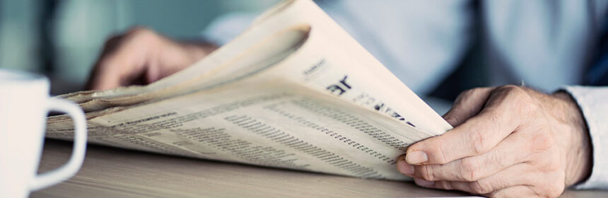 Man sitting at table with coffee reading the newspaper