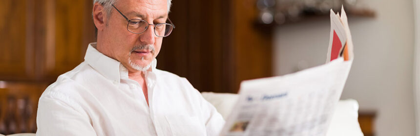 Man sitting on couch reading the newspaper