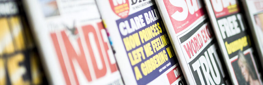 Close up of row of newspapers on news stand