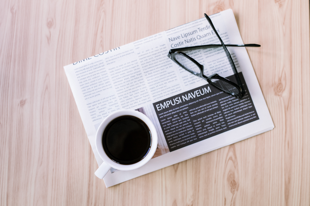 A newspaper with glasses and a cup of coffee